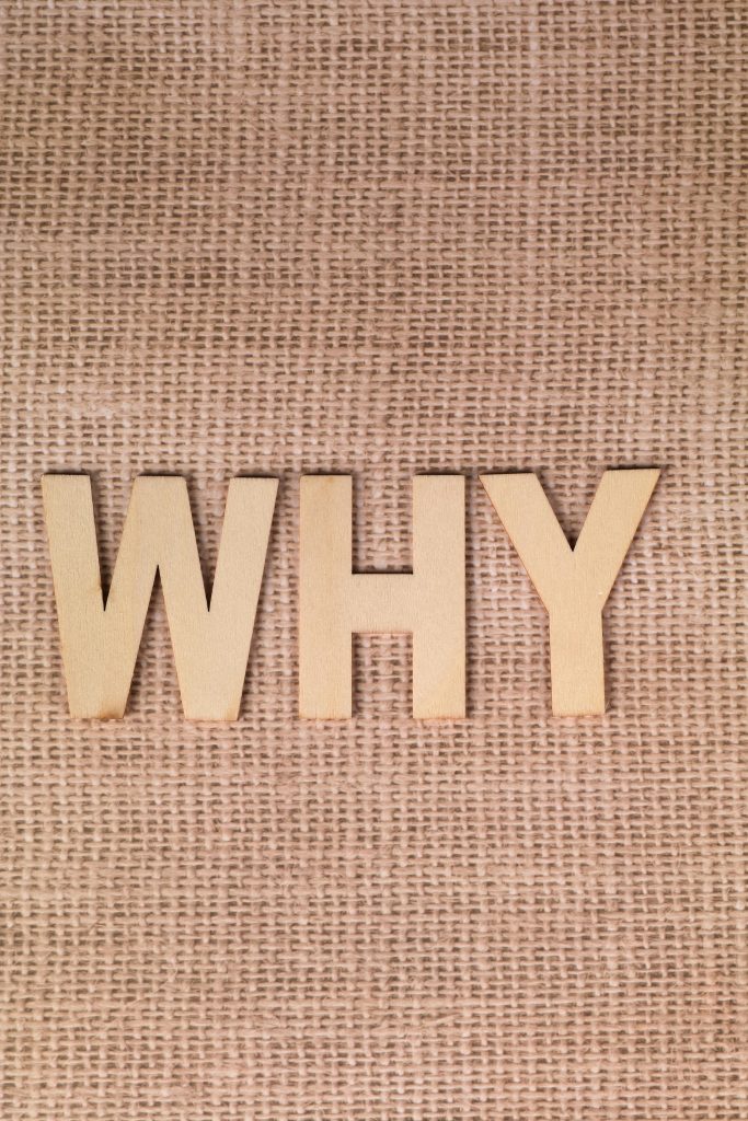 Wooden letters spelling 'WHY' placed against a textured burlap background, offering a rustic and contemplative feel.