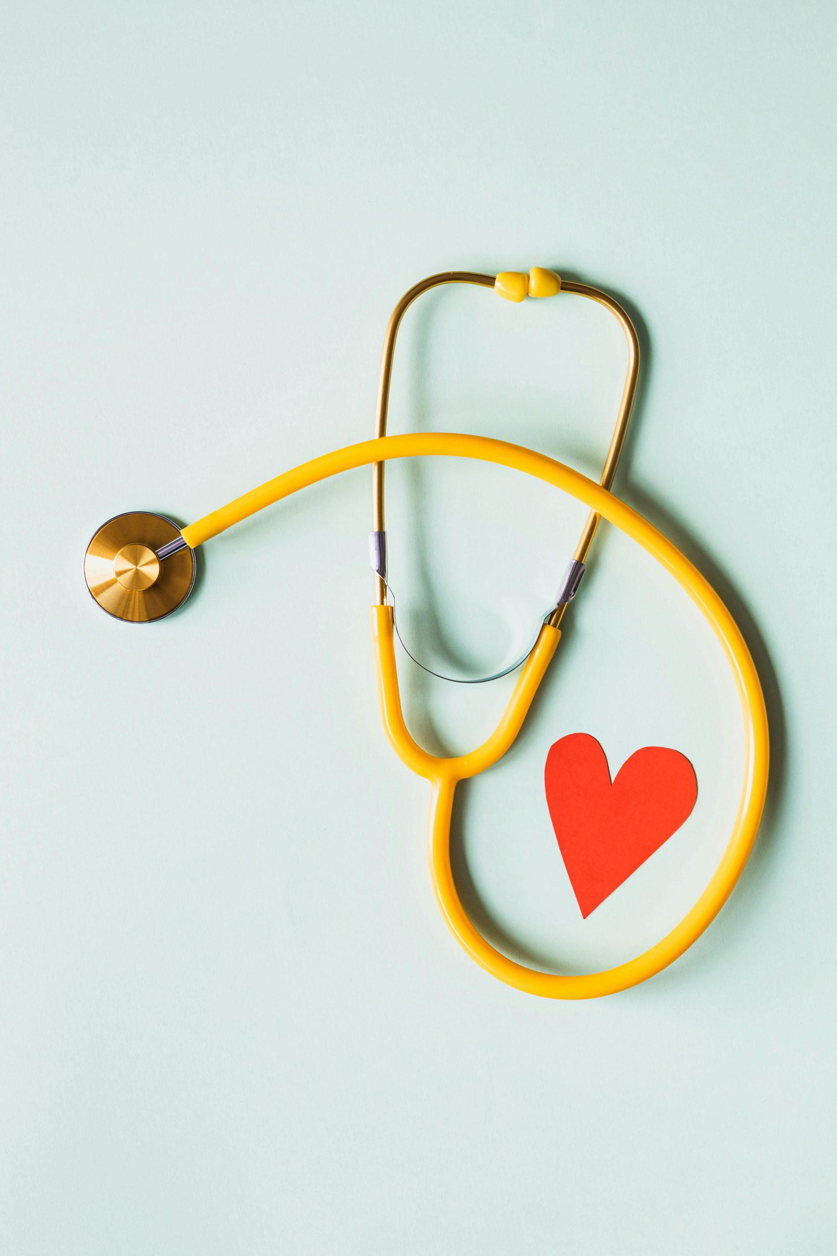 Paper red heart placed on white background with yellow medical stethoscope for heart care