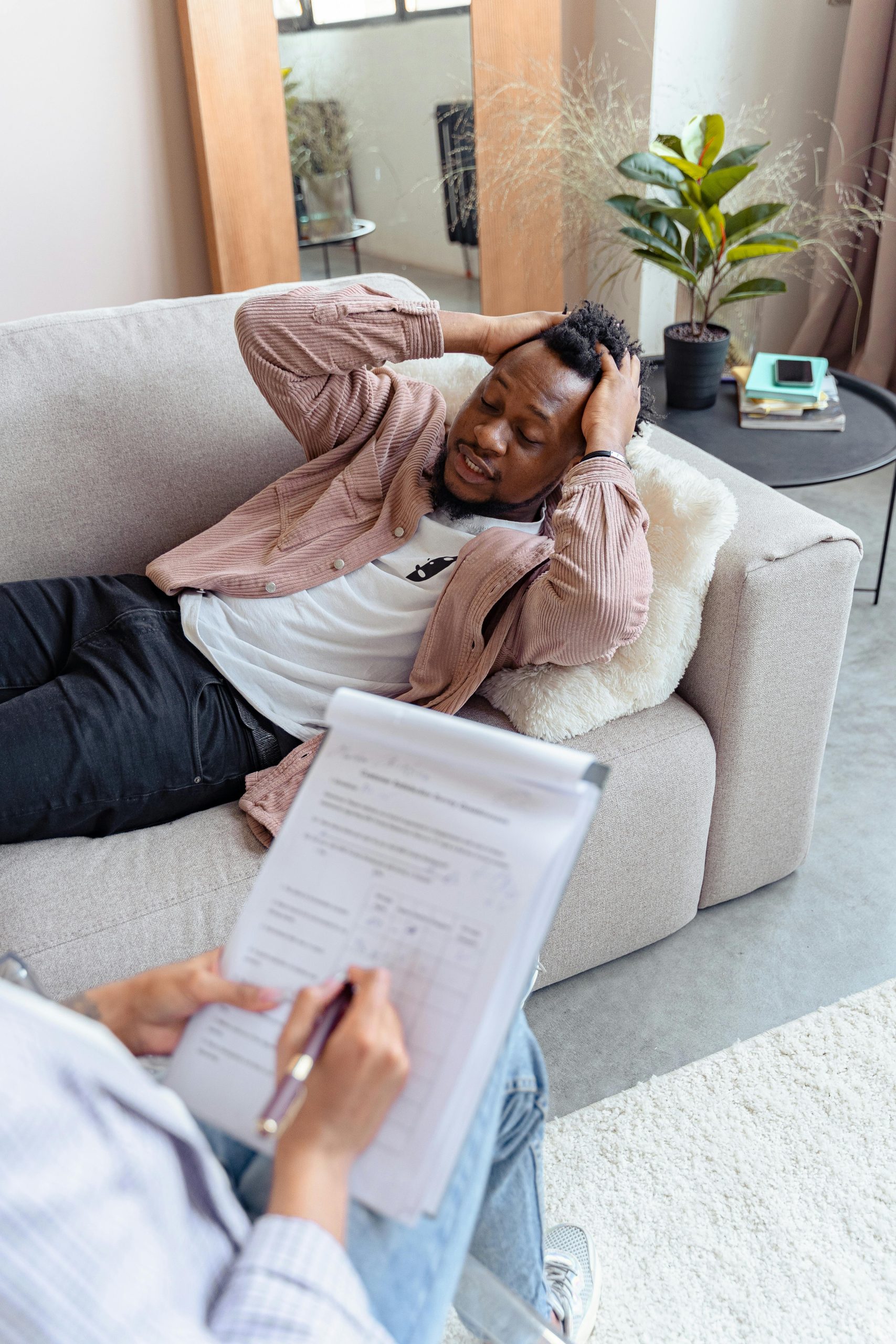A therapist sessions with a worried man lying on a sofa, addressing mental health concerns.